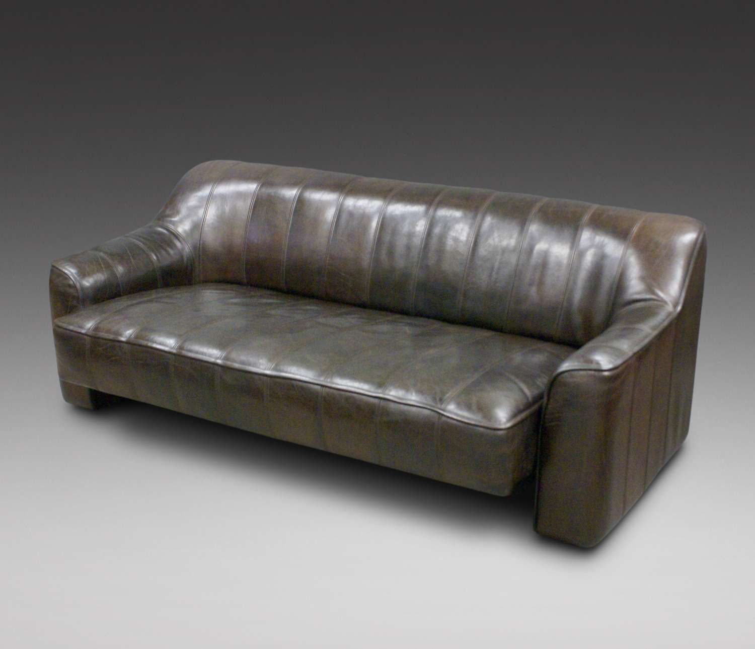A Leather sofa, arm chair and foot stool by De Sede